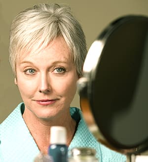 Person with short hair looking in mirror.