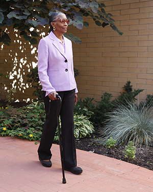 Woman with cane walking outdoors.